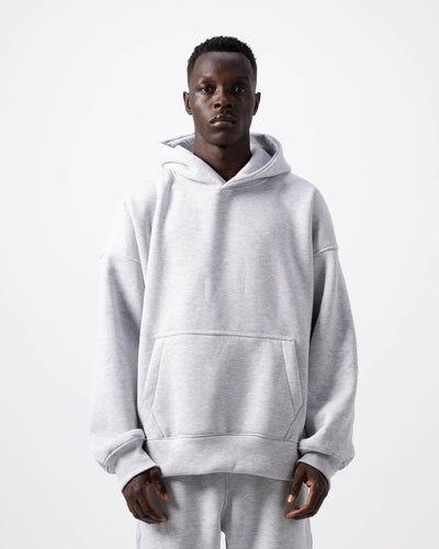 Person wearing a gray hoodie and pants set on a white background