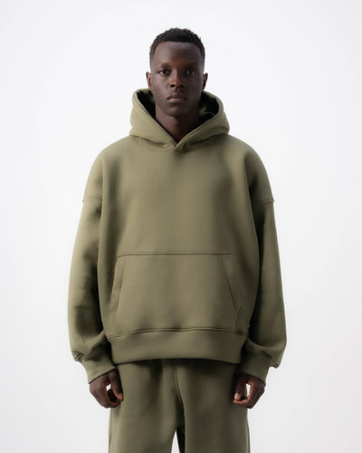Person wearing a green hoodie and pants on a white background