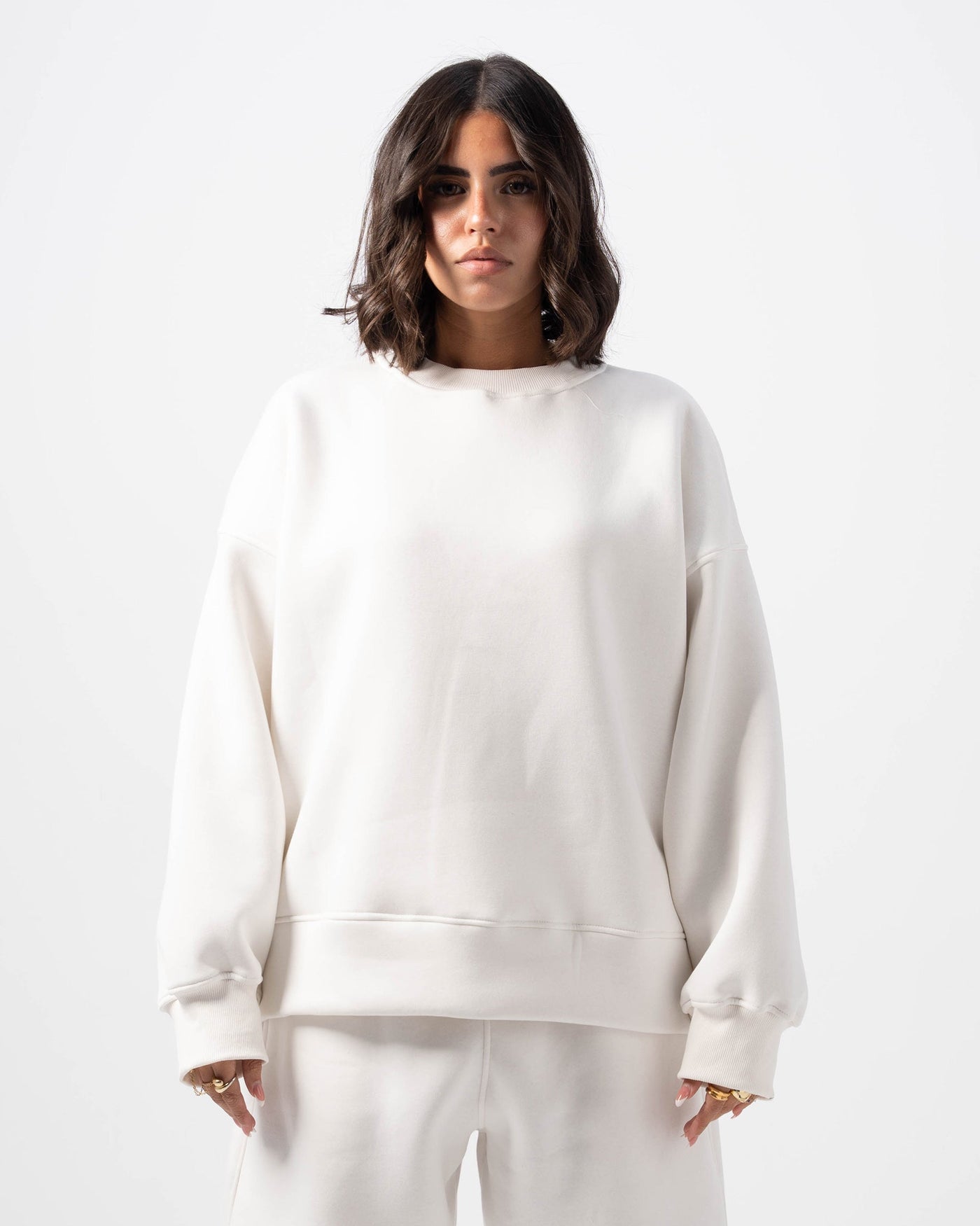 Person wearing a white sweatshirt and pants set on a white background